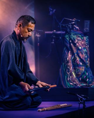 A performer prepares for a meditative musical session on stage at the HOLOLIFE Summit.