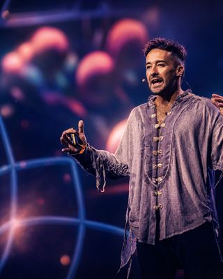 Speaker presenting on stage with vibrant visuals in the backdrop at the HOLOLIFE Summit 2026.