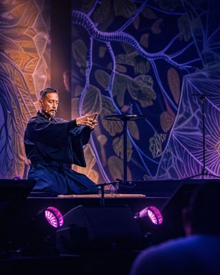 A performer demonstrating a traditional art form on stage, creating a serene atmosphere during the HOLOLIFE Summit.