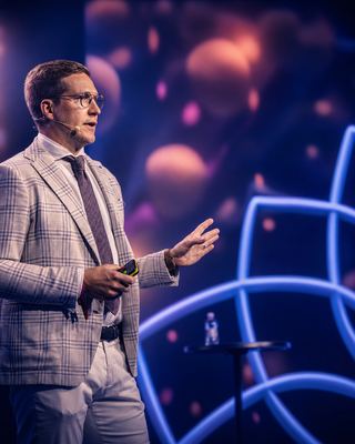 A speaker passionately engaging the audience at the HOLOLIFE Summit 2026 in Amsterdam.