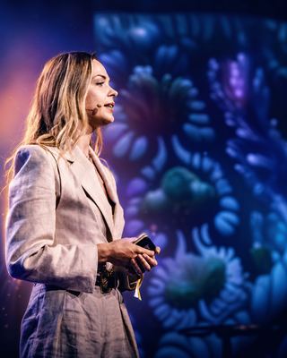 A speaker presenting on stage with vibrant visuals in the background at the HOLOLIFE Summit.
