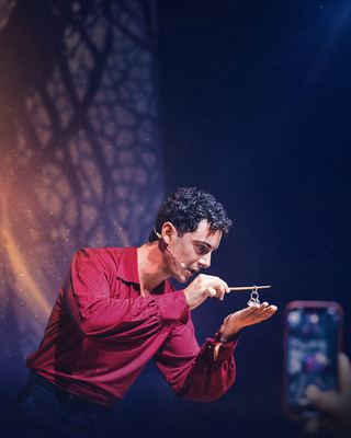 A captivating magician performing an engaging illusion on stage during the HOLOLIFE Summit 2026.