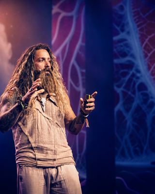 A speaker passionately presenting on stage at the HOLOLIFE Summit 2026 in Amsterdam.