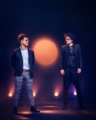 Two speakers engage in a dynamic exchange on stage, illuminated by vibrant lights at the HOLOLIFE Summit.