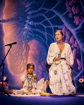 A speaker and a young girl present on stage, showcasing cultural heritage within the wellness space.