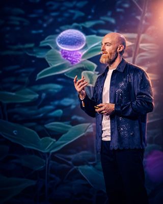A speaker passionately presents innovative concepts related to longevity against a visually engaging backdrop.