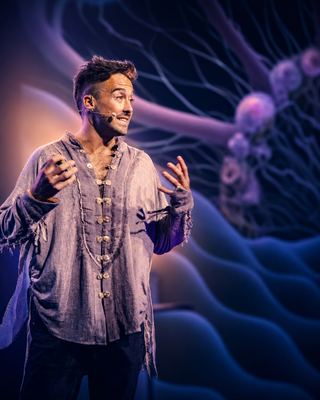 A speaker passionately engages the audience during a session at the HOLOLIFE Summit, with a dynamic backdrop.