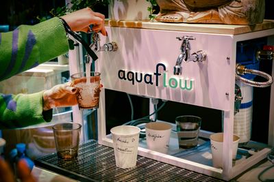 Attendees enjoying refreshing beverages at the aquaflow booth during the HOLOLIFE Summit 2025.