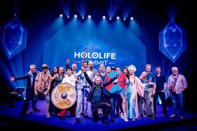 A vibrant group photo of speakers celebrating the HOLOLIFE Summit, showcasing energy and community.