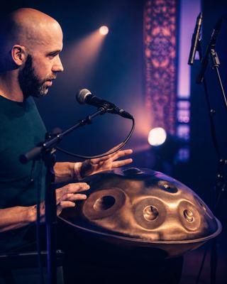 A musician performing with a handpan at the HOLOLIFE Summit, enriching the ambiance with soothing melodies.