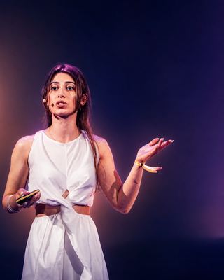 A speaker passionately presenting on stage at the HOLOLIFE Summit 2026 in Amsterdam.