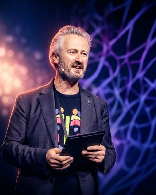 A speaker engaging the audience during a keynote address at the HOLOLIFE Summit 2026.