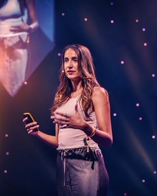 Speaker delivers a session on stage at the HOLOLIFE Summit 2026 in a vibrant atmosphere.